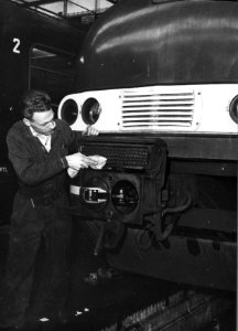 HUA-159380-Afbeelding van een onderhoudsmonteur tijdens werkzaamheden aan de automatische koppeling van een electrisch treinstel plan T (mat. 1964) van de N.S. in de lijnwerkplaats te Leidschendam
