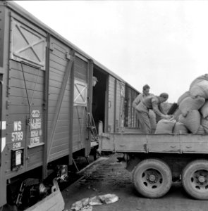 HUA-167051-Afbeelding van het overladen van zakken graan van vrachtauto naar goederenwagens van de N.S. te Amersfoort