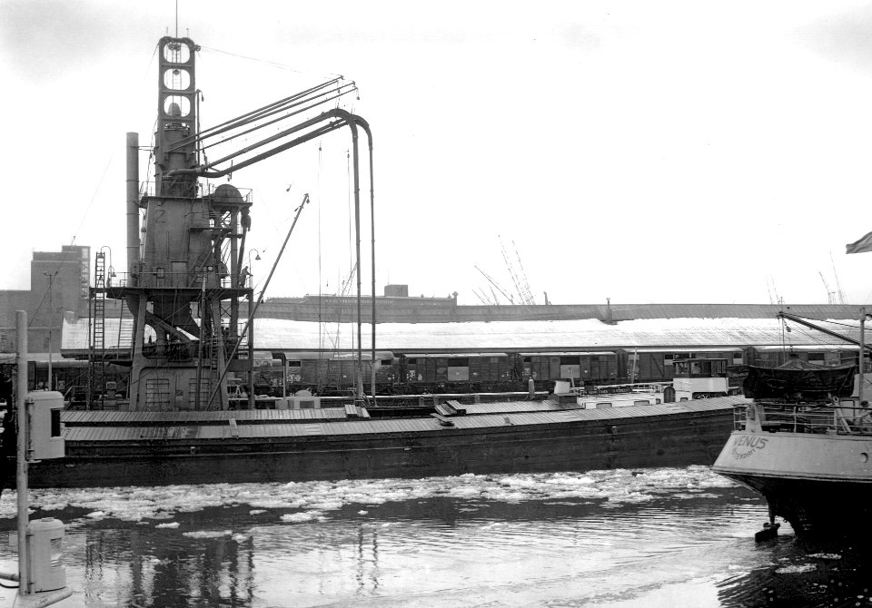 HUA-167001-Afbeelding van het overladen graan van schip naar trein via een elevator in de haven van Rotterdam
