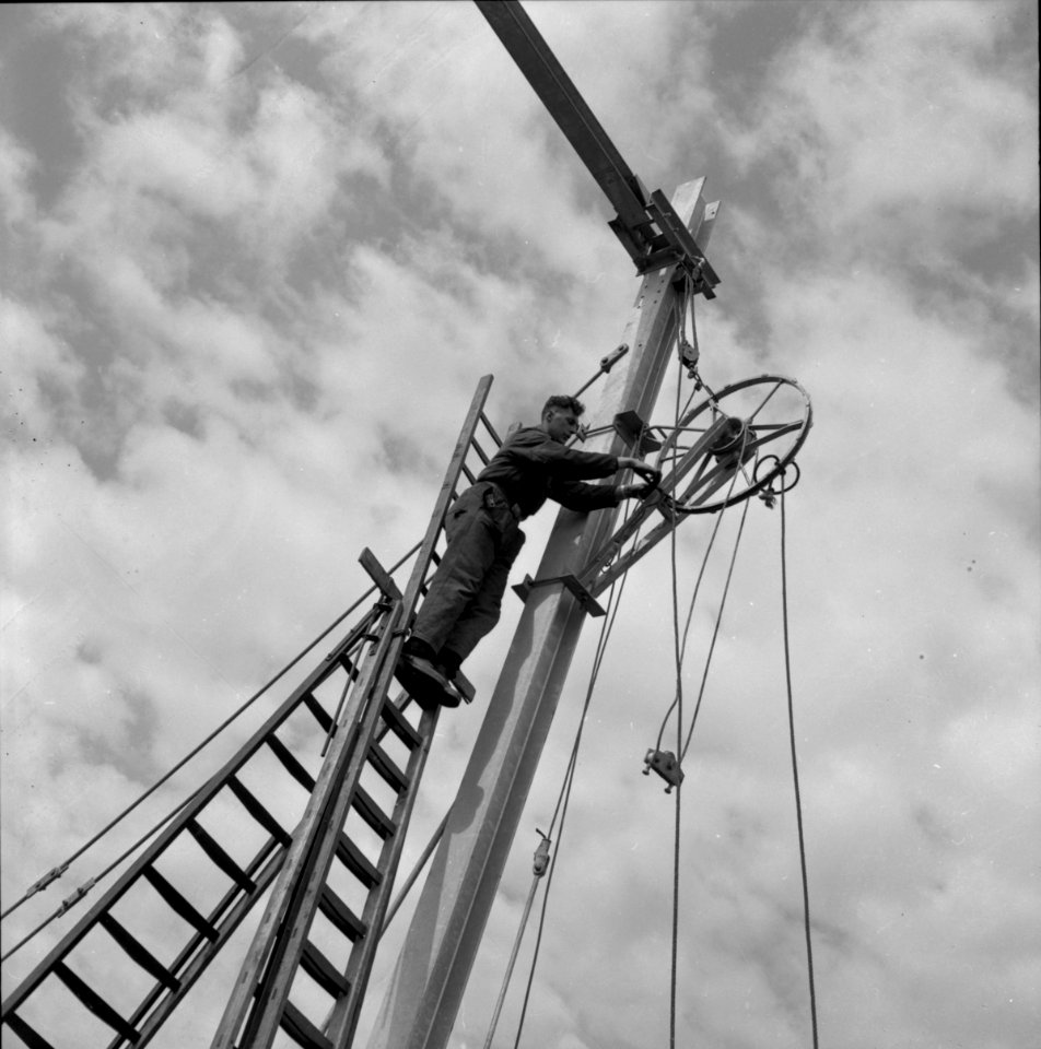 HUA-166494-Afbeelding van het plaatsen van een afspanwiel aan een bovenleidingsportaal te Wouw, tijdens de werkzaamheden ten behoeve van de electrificatie van de spoorlijn Roosendaal-Vlissingen