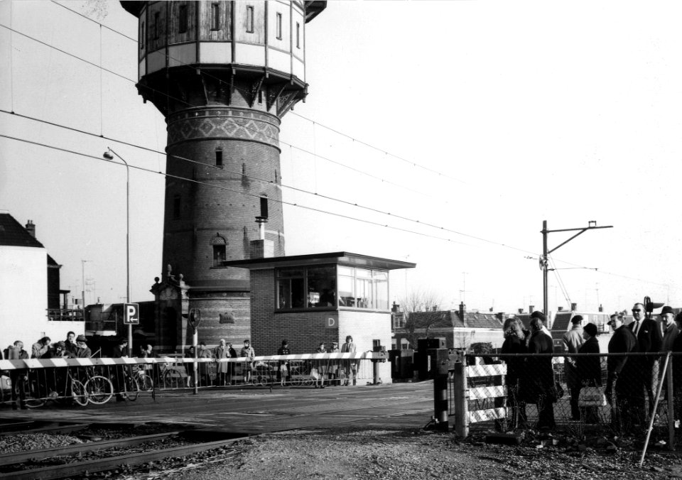 HUA-166550-Gezicht op de spoorwegovergang in de Schrans te Leeuwarden met op de achtergrond het seinhuis Post D en de in 1972 afgebroken watertoren