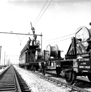 HUA-166485-Afbeelding van een werktrein van de NS bestaande uit een montagewagen en haspelwagens tijdens het aanbrengen van de bovenleiding boven een spoorlijn