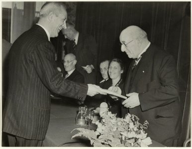 Hoofdwacht. Dr. C. Spoelder overhandigd het eerste exemplaar van de geschiedenis van de Haarlemse Hofjes, geschreven door Dr. G.h. Kurtz, aan burgemeester Cremers. NL-HlmNHA 54019340