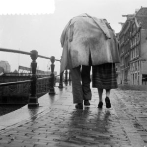 Hoogwater te Amsterdam. Regenval. Paartje loopt langs de Amstel, Bestanddeelnr 904-7204