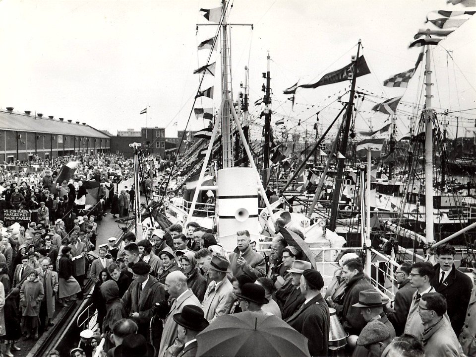 In de Vissershaven werd vlaggetjesdag gevierd met een optocht langs minister Mansholt (achter de microfoon). Aangekocht in 1977 van fotograaf C. de Boer. Identificatienummer 54-005542