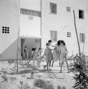 In een nieuwbouwwijk in Dimona Vrouwen en kinderen voor een flatgebouw met bove, Bestanddeelnr 255-3574