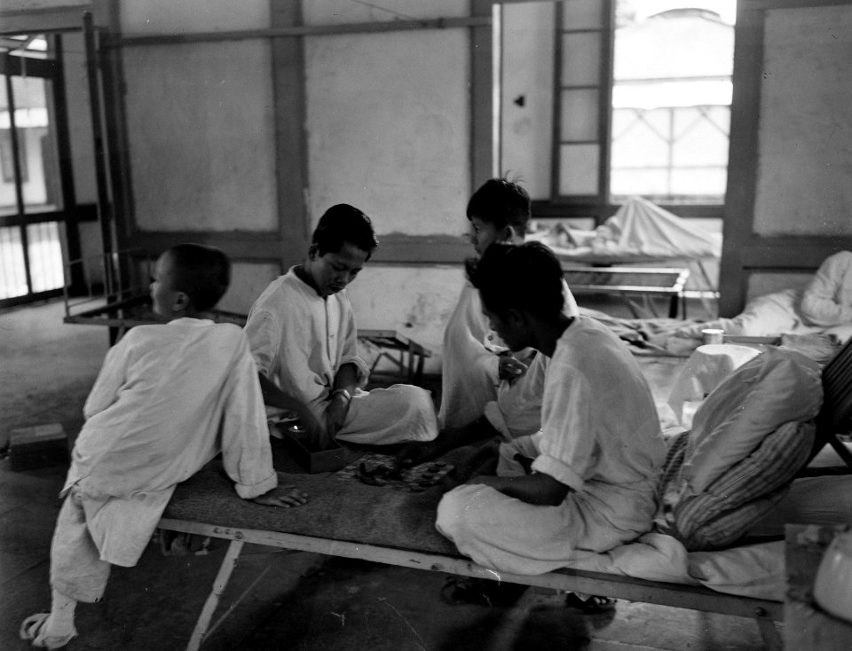 In een(zieken)bara zitten in het wit geklede Indonesische jongens op een bed en, Bestanddeelnr 10479