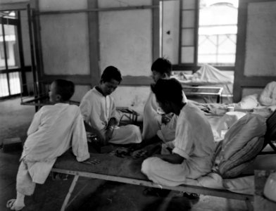 In een(zieken)bara zitten in het wit geklede Indonesische jongens op een bed en, Bestanddeelnr 10479