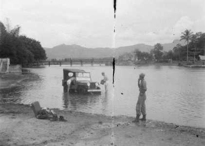 In een rivier wordt een jeep van de Militaire Politie gewassen. In de achtergro, Bestanddeelnr 7241