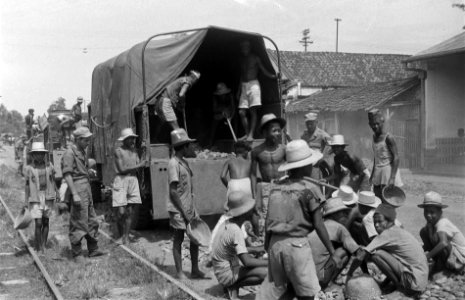 Indonesische jongens werken als koelies aan wegherstel Achter hen een militaire, Bestanddeelnr 6614