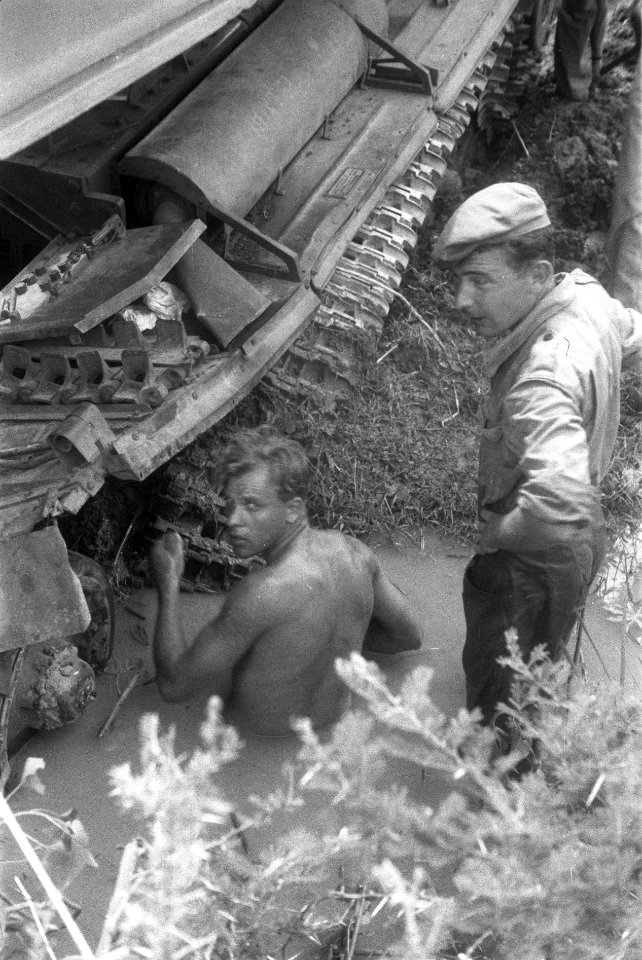 In de modder probeert een militair met hamer en beitel iets los te bikken van e, Bestanddeelnr 257