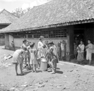 Indonesische vrouwen en kinderen bij melk-uitdeling in een kampong, Bestanddeelnr 254-5446