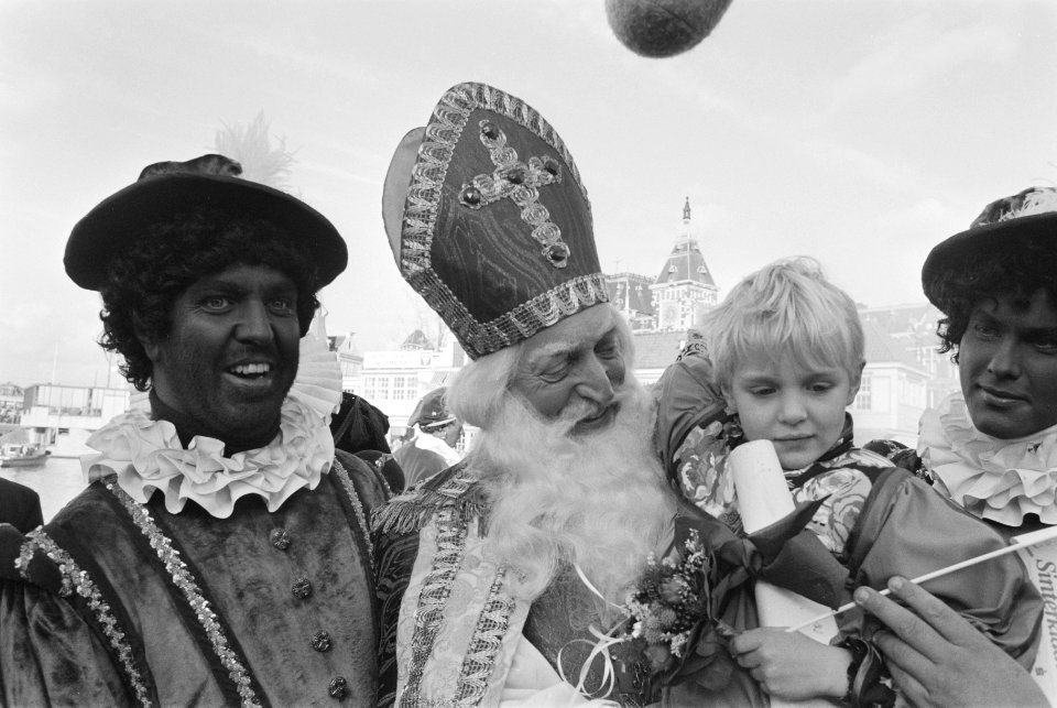 Intocht Sinterklaas in Amsterdam Sint met kind op de arm en Zwarte Piet, Bestanddeelnr 934-1289