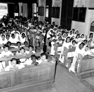Interieur van de Rooms-Katholieke kerk in Nieuw-Nickerie. Schoolkinderen doen hu, Bestanddeelnr 252-5473