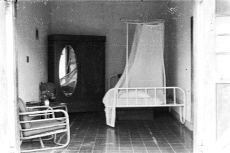 Interieur van een kamer met openslaande deuren. Te zien zijn een metalen bed met, Bestanddeelnr 6069