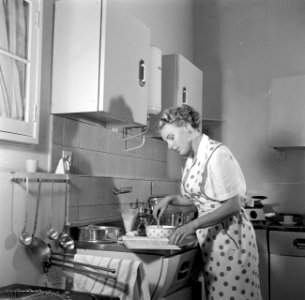 Huisvrouw in modelkeuken bezig met het maken van een taart., Bestanddeelnr 252-1650