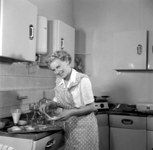 Huisvrouw in modelkeuken bezig met het maken van een taart., Bestanddeelnr 252-1643