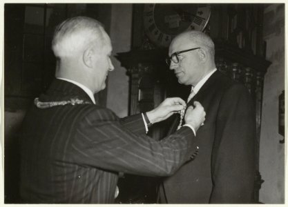 Huldiging van de heer B.J. Thijssen (gem. ontvanger) op het stadhuis n.a.v. zijn 40-jarig jubileum. Burgemeester Cremers speldde hem een koninlkijke onderscheiding op. NL-HlmNHA 54002659