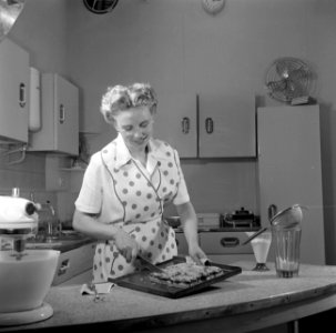 Huisvrouw in modelkeuken bezig met het maken van een taart., Bestanddeelnr 252-1646