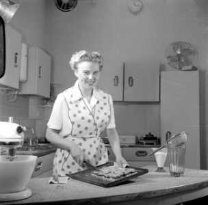 Huisvrouw in modelkeuken bezig met het maken van een taart., Bestanddeelnr 252-1648