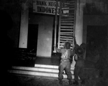 In het donker verwijderen soldaten de hordeuren van een gebouw met opschrift Ban, Bestanddeelnr 11651