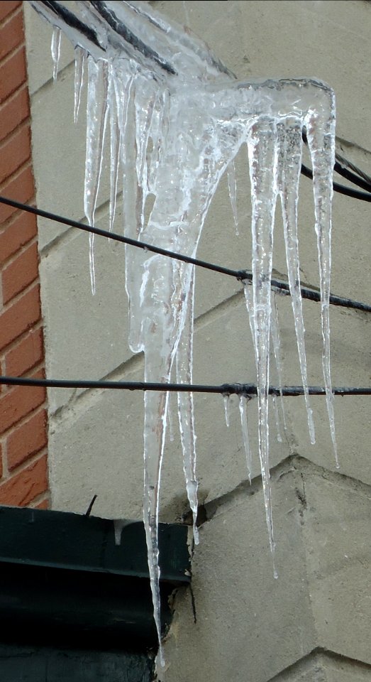 Icicles hanging from wires in winter from a house