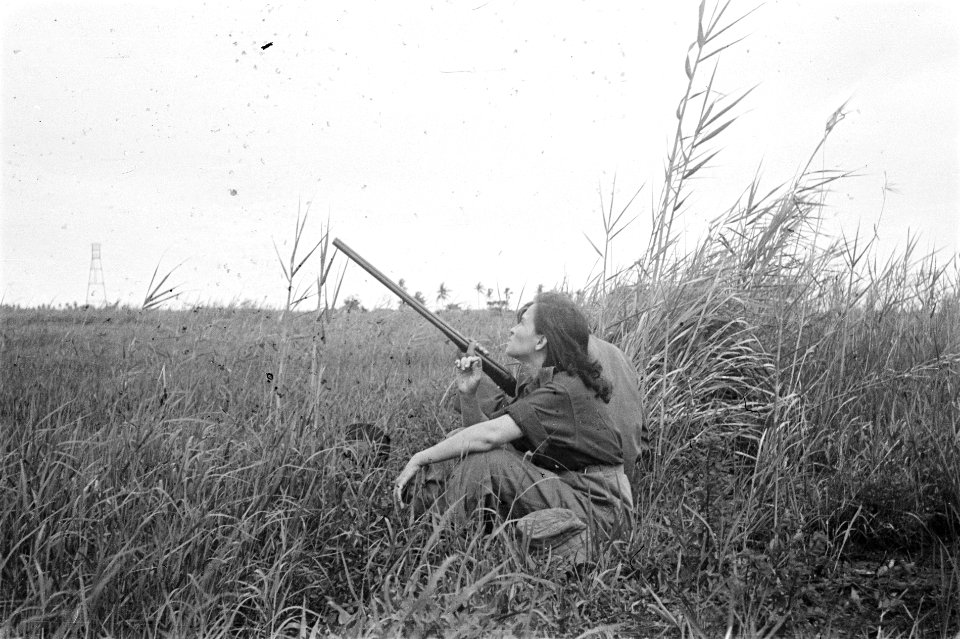 Jonge vrouw en Indonesische man in uniform zitten naast elkaar in een veld. De m, Bestanddeelnr 6091