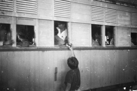 Jonge verkoper reikt iets uit aan iemand in de trein, Bestanddeelnr 1510-4-1
