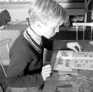 Jongen bezig met een postzegelverzameling, Bestanddeelnr 252-8771