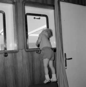 Jongetje aan boord van een schip kijkt door een raampje naar buiten, Bestanddeelnr 255-4962