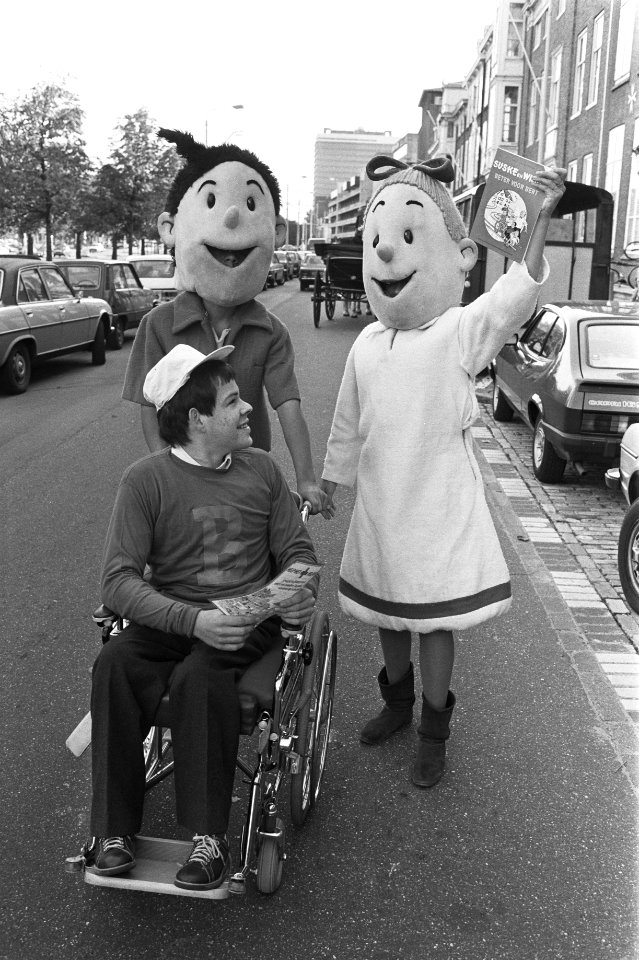 Jongen in een rolstoel met daarachter de stripfiguren Suske en Wiske, met het al, Bestanddeelnr 932-7376