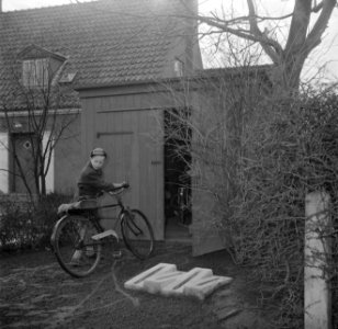 Jongen met fiets op een tuinpad bij een schuur en fietsenrekken, Bestanddeelnr 252-8734 photo