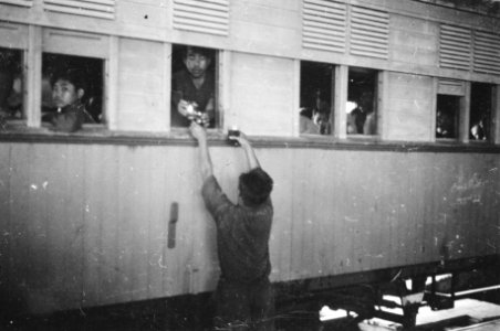 Jonge verkoper reikt iets uit aan iemand in de trein, Bestanddeelnr 1510-4-2