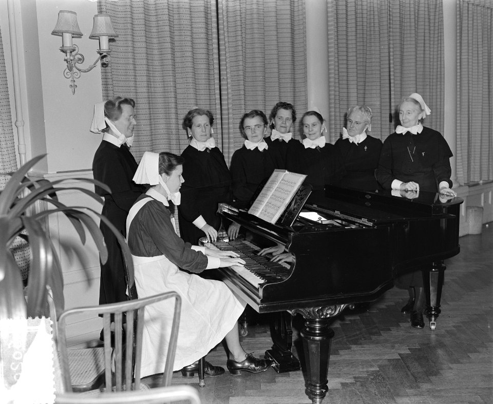Jubilea in Diaconessenhuis Amsterdam. Zeven diaconessen bij een piano, Bestanddeelnr 906-0209