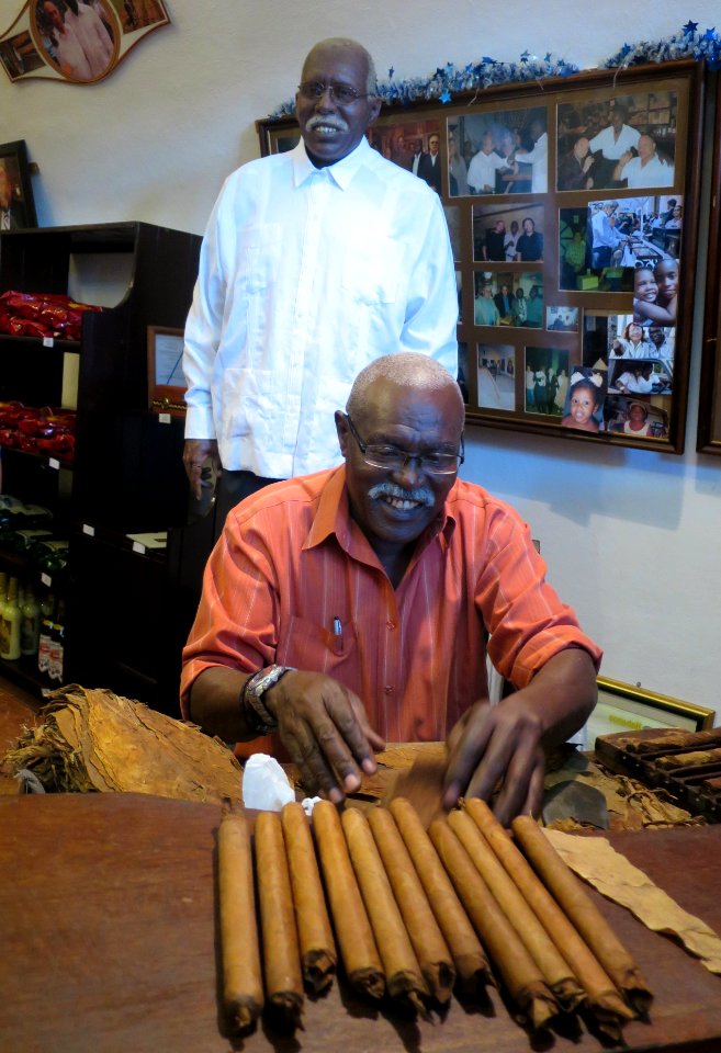 Jose Castelar making cigars in front of a statue of himself