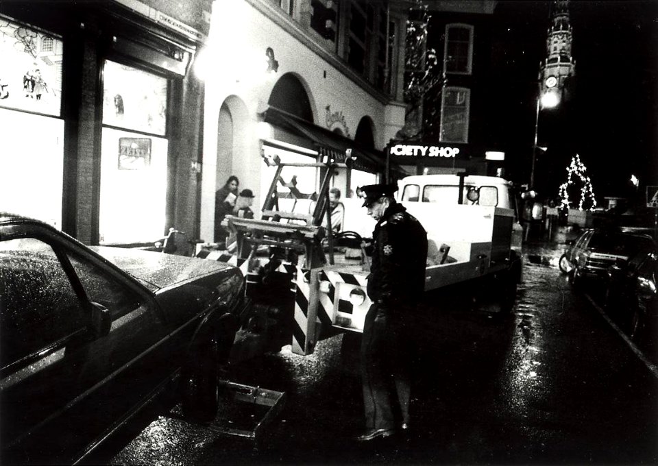 J. Melchior van de parkeerpolitie bij een sleepactie in de Zijlstraat. Aangekocht van United Photos de Boer bv. - Negatiefnummer 33520 k 17. - Gepubliceerd in het Haarlems Dagblad van 21-12-1990. Iden