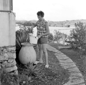 Jannetje schept regenwater uit een pot bij een huis aan de Fuikbaai, Bestanddeelnr 252-3031