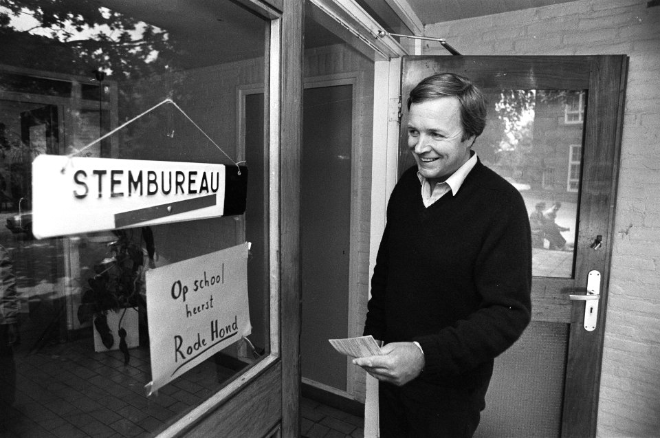 Jan Terlouw (D66) leest bij het stembureau een bord met het opschrift Op schoo, Bestanddeelnr 932-3158