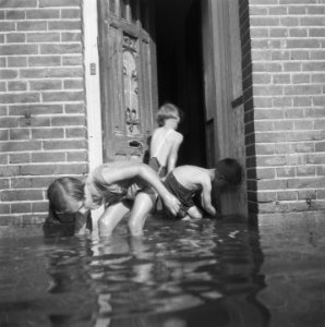 Kinderen spelen bij de voordeur van een woning in een ondergelopen straat, Bestanddeelnr 900-7616