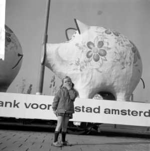 Kind dat voor een van de reuzegrote spaarvarkens op een aanhangwagen staat, Bestanddeelnr 918-3611