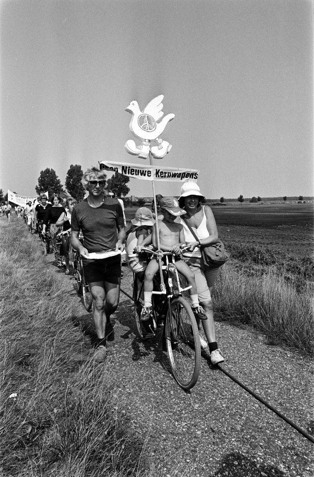 Kinderen in fietsstoeltjes op een fiets versierd met een vredesduif, Bestanddeelnr 932-6699