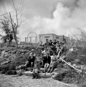 Kinderen en een begeleidster van het kinderdorp Oniem, zittend op een trap, Bestanddeelnr 255-0516