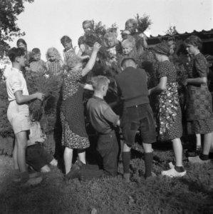 Kinderen en vrouwen bezig om iets te versieren met struikhei, Bestanddeelnr 900-7385
