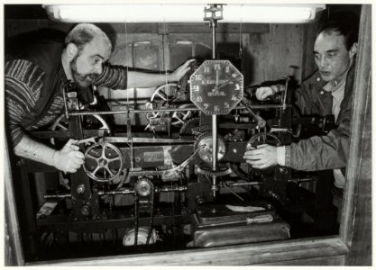 Kees van Veen (links) en Arthur Cobelens passen het uurwerk van de Grote of St. Bavokerk aan de wintertijd aan. NL-HlmNHA 54037110