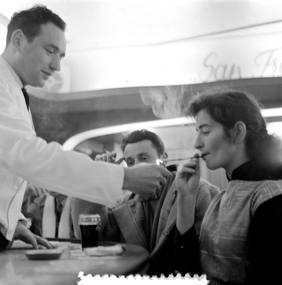 Kelner geeft een vrouw een vuurtje in een horeca-gelegenheid op de Zeedijk, Bestanddeelnr 907-5555