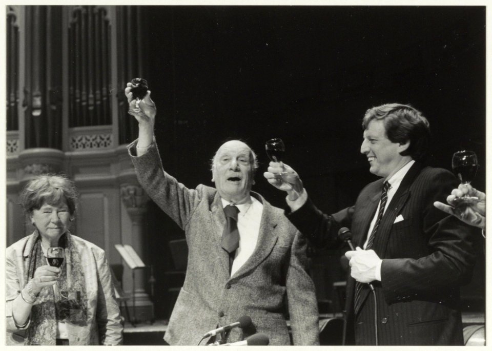 Kees verwey en echtgenote heffen het glas tegenover het publiek in het Concertgebouw nadat de eerste fles Verwey -wijn was uitgeschonken. NL-HlmNHA 54015515