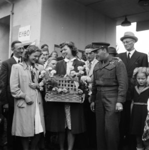 Kermis Vrouw ontvangt mand met bloemen Zij wordt omringd door een groep mensen, Bestanddeelnr 900-7640