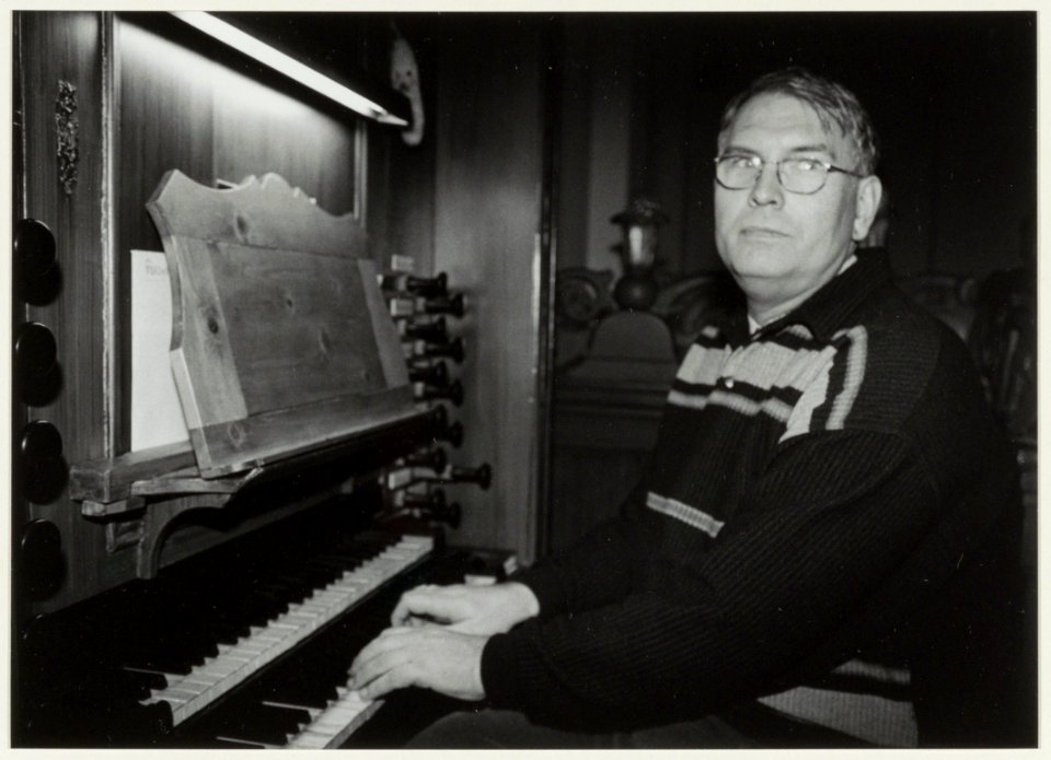 Kerkorganist Willem Wijting op zijn favoriete plek in de Nieuwe Kerk, aan het Hessvan Covelen-orgel. Toen hij 25 jaar verbonden was aan de Nieuwe Kerk, werd hij onderscheiden met het zilver, NL-HlmNHA 54037059