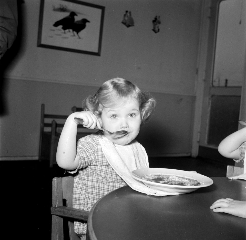 Kleuter zit aan een tafeltje te eten, Bestanddeelnr 252-9096