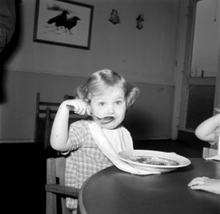 Kleuter zit aan een tafeltje te eten, Bestanddeelnr 252-9096